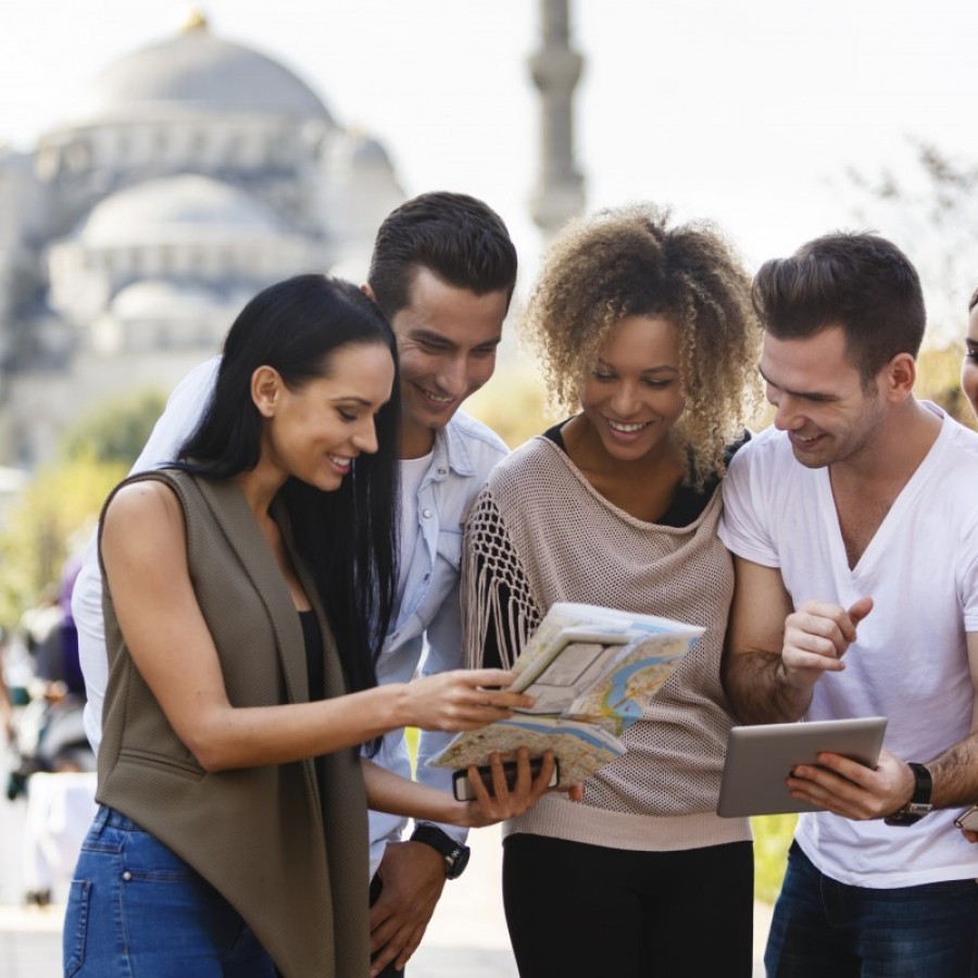 Group of happy tourists with digital tablet and a map in Sultanahmet district in Istanbul, Turkey. Blue mosque is in the background.
